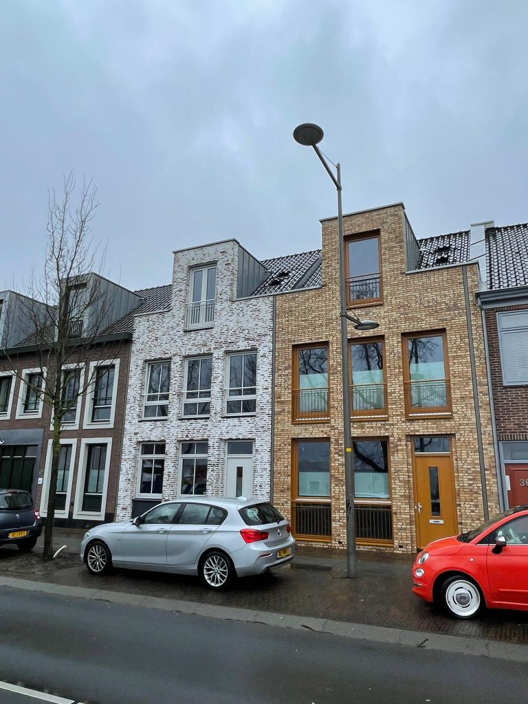 De nieuwe woningen in de bestaande straatwand, gezien over de weg