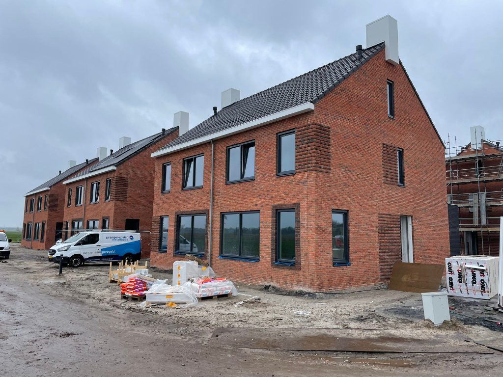 Rij nieuwbouwwoningen in rode baksteen, vrijwel gereed