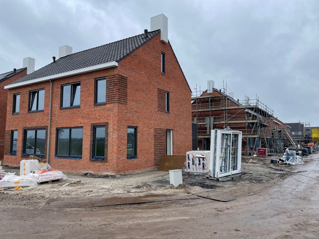 Rode baksteenwoningen in aanbouw met steigers en bouwmateriaal op het terrein