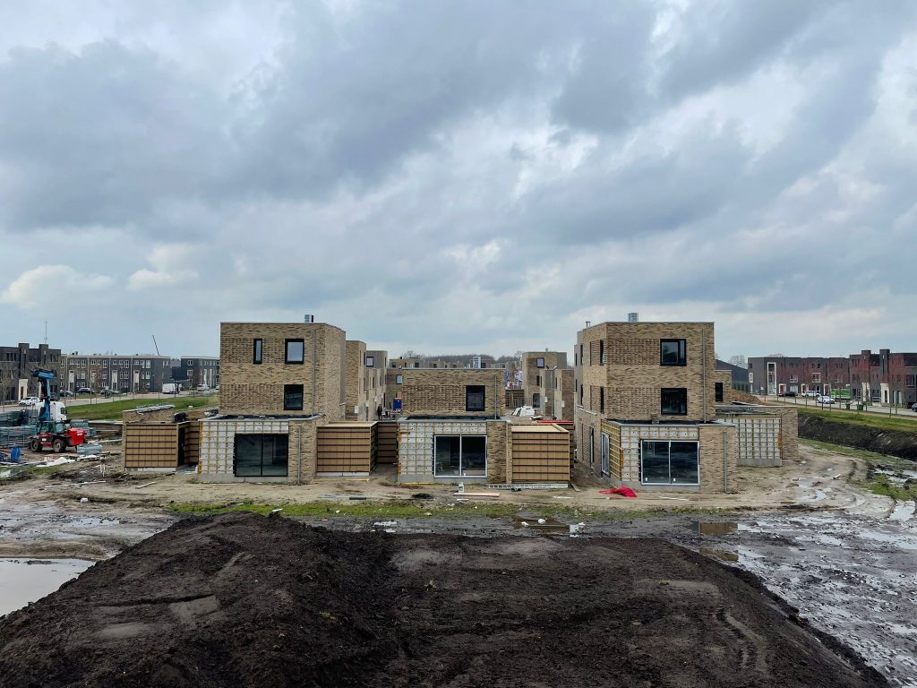 Twee blokken nieuwbouwwoningen in aanbouw op een nog onverharde bouwplaats