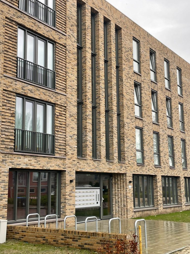 Hoek van het appartementengebouw met de entreepartij en hoge raamopeningen