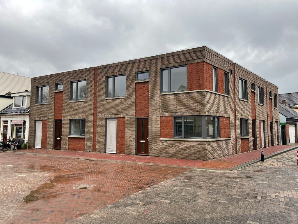 Hoekblok van vier woningen in lichte baksteen met rode baksteenbanden